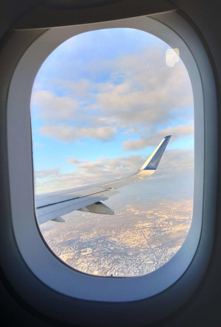 Photo of an airplane window showing a pastel, sunny city of Los Angeles.