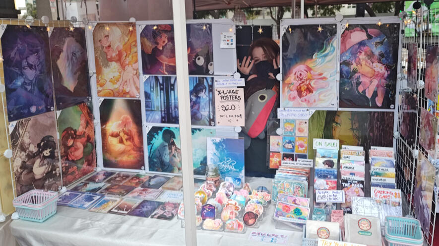 Photo of Aryssa's tabling setup for selling art prints and stickers at in-person events.