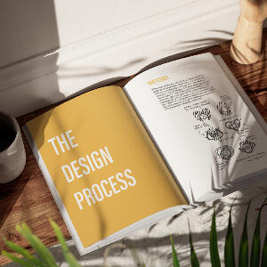 A mockup of a branding redesign process book open to a page with the text, "The Design Process" on the left and sketches of logo redesigns on the right.